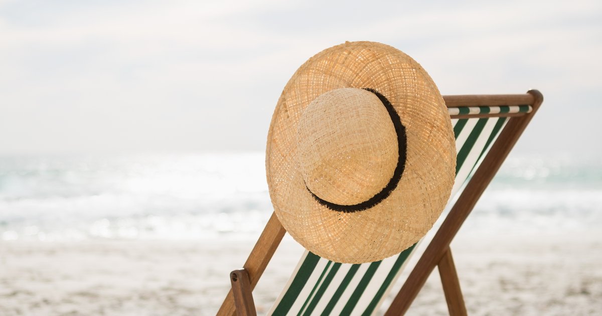 Chapéu de palha em uma cadeira de praia, lembrando a importância da proteção solar no verão
