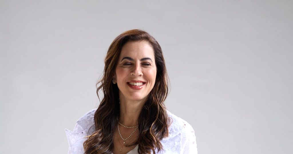 Dra. Renata Mitelman, dermatologista em Perdizes, São Paulo, sorrindo, em um ambiente claro da clínica